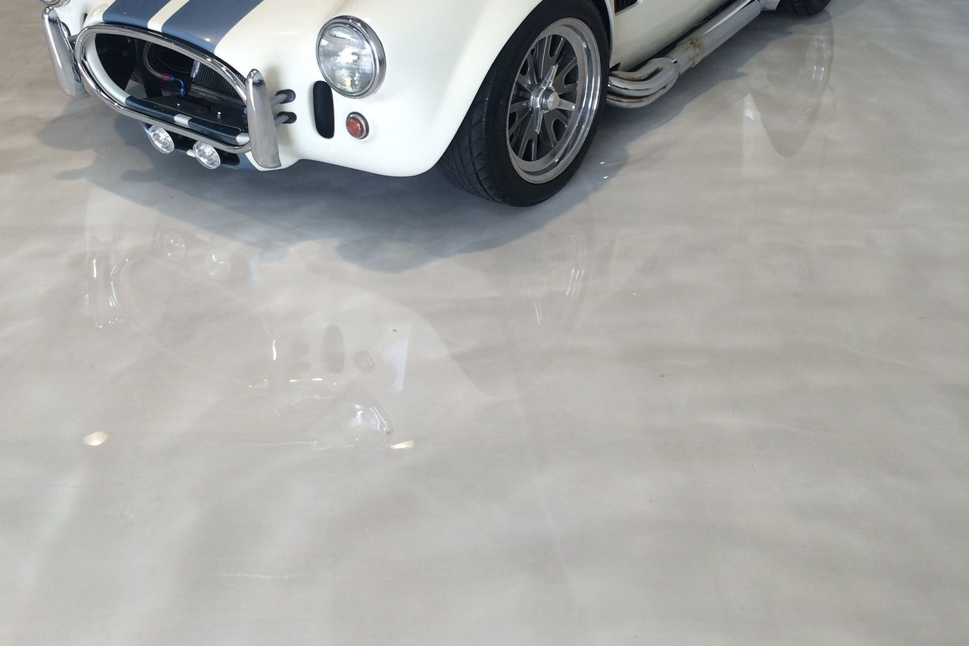 a white metallic garage floor with a classic car on it